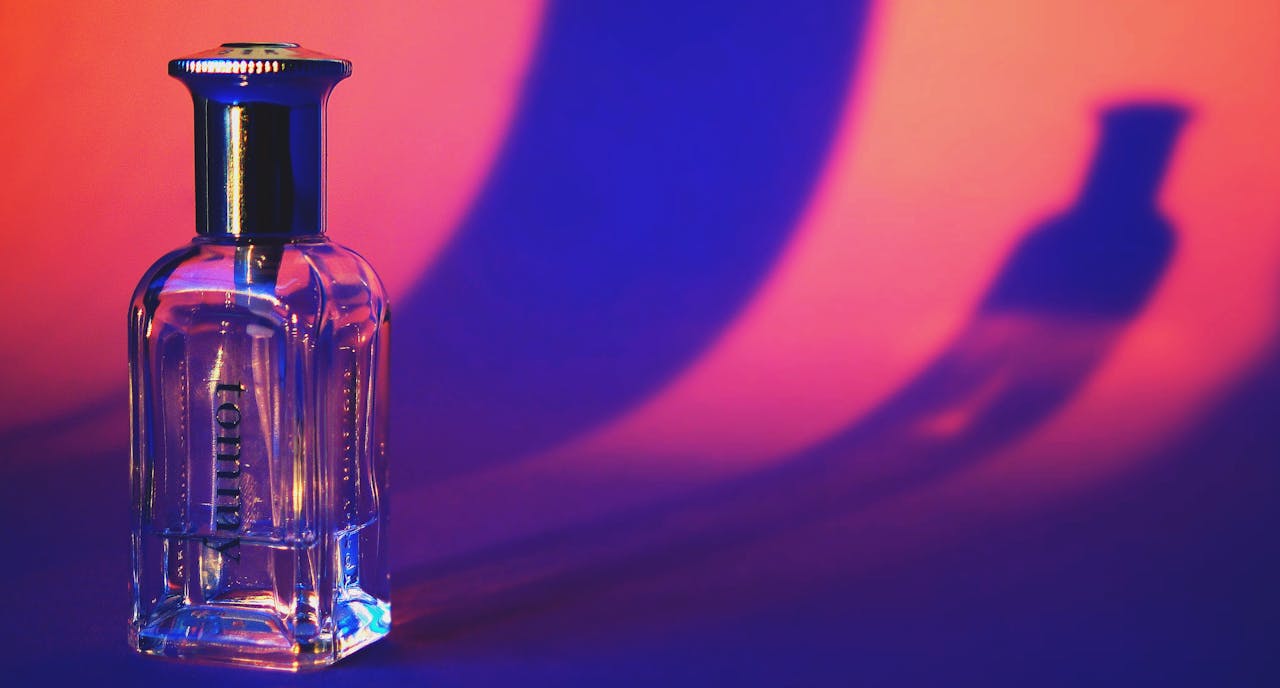 A glass perfume bottle casting vibrant shadows in a colorful setting.